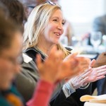 Blonde woman wearing glasses on top of her head smiling and laughing